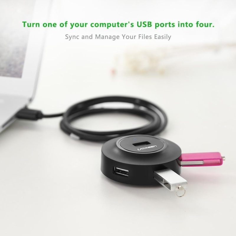 Hub USB Ugreen de 4 puertos conectando múltiples dispositivos USB en una laptop.