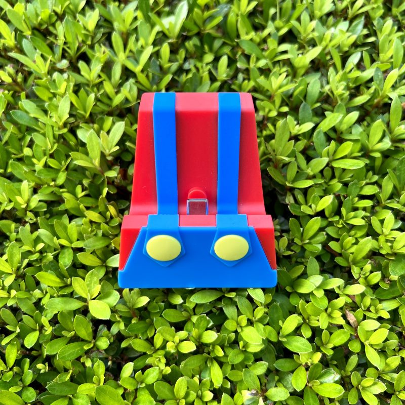 Base de carga portátil Mario Bros para Nintendo Switch con puerto Tipo C sobre un fondo de plantas verdes.